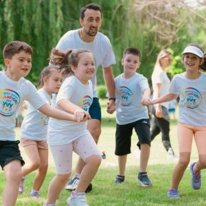 Children joyfully running and holding hands in a sunny park, enjoying outdoor recreation.